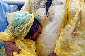 A woman and her child, both wearing rain ponchos, attend a mass led by Pope Francis near Tacloban airport on Saturday. The pontiff proceeded with his scheduled visit to Leyte despite the storm, to console with the victims of super typhoon Yolanda that killed 6,300 people barely a year ago. (MNS photo)