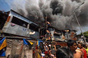 Residents use a thin pole to climb to the rooftops of their houses so they can battle the fire in Parola compound in Tondo, Manila. Two fires in succession hit the area occupied by thousands of shanties, rendering almost 10,000 families homeless and living in temporary shelters. (MNS Photo)