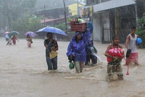 Residents clutch to their belongings as they wade along a flooded road after tropical storm Egay hit the coastal town of San Fernando, La Union on Monday. All sea travel and fishing operations in the north were suspended as sea waves reached as high as 4 meters. (MNS photo)