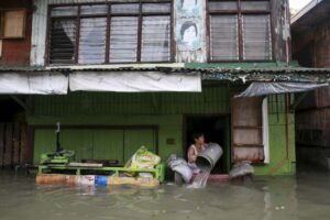 A woman clears flood water that entered her home, caused by tropical storm Egay at Longos town in Malabon City on Monday. Classes were suspended in Metro Manila and 14 areas in Luzon due to flooding and landslides while all shipping and flights were canceled as Egay moved slowly accross the country.(MNS photo)